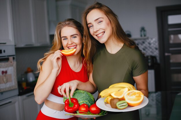 Chica de dos deportes en una cocina con verduras