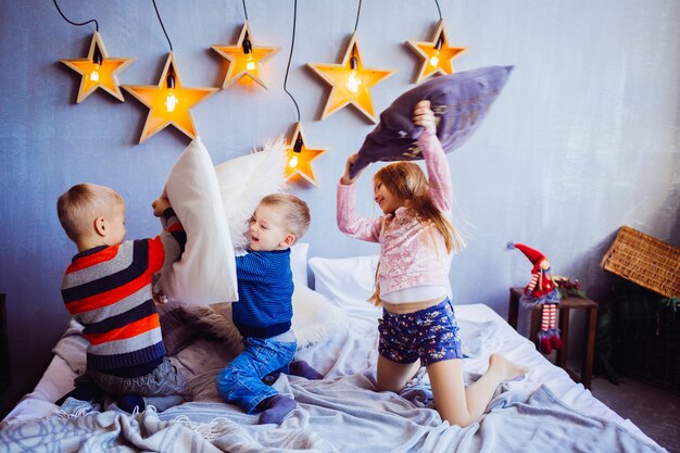 La chica dulce y los niños jugando y saltando en la cama