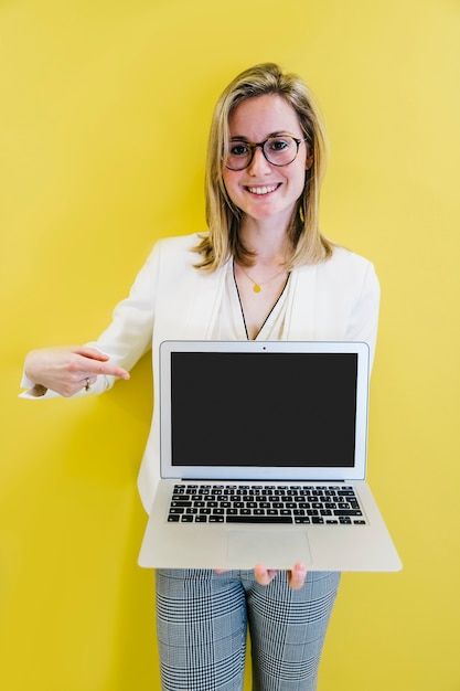 Chica elegante apuntando a la pantalla de la computadora portátil