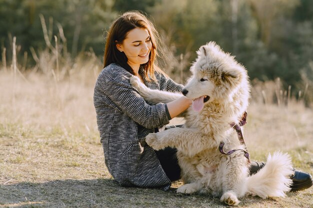 Chica elegante en un campo soleado con un perro