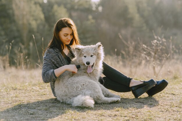 Chica elegante en un campo soleado con un perro