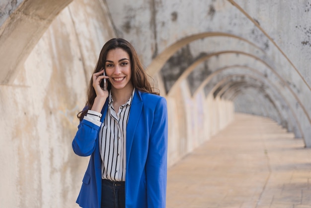 Chica elegante con chaqueta azul hablando por teléfono