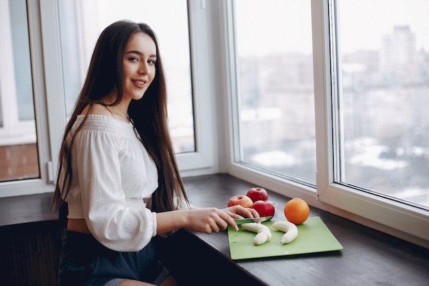 Chica elegante en una cocina con frutas.