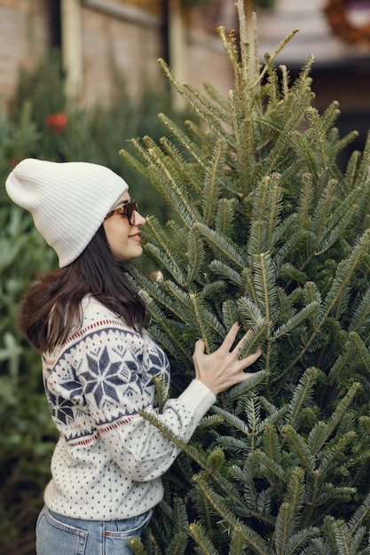 Chica elegante compra un árbol de Navidad.