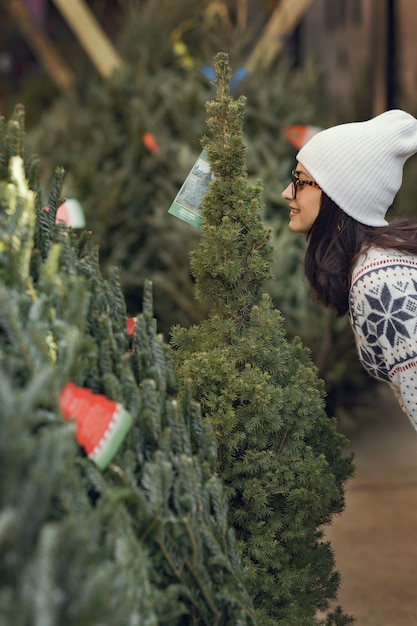 Chica elegante compra un árbol de Navidad.