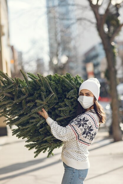 Chica elegante compra un árbol de Navidad.