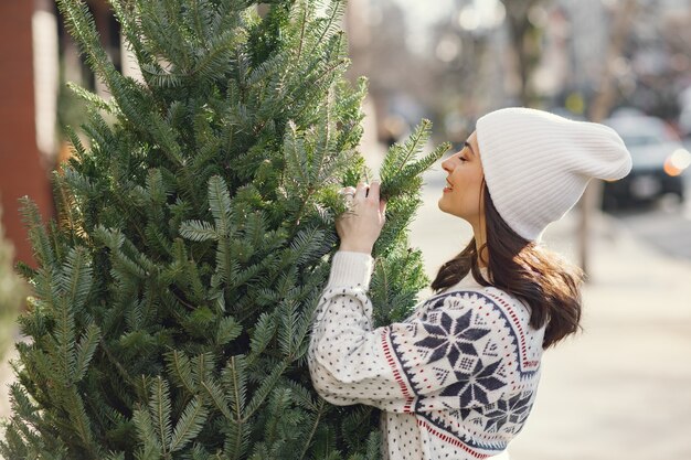 Chica elegante compra un árbol de Navidad.