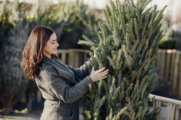 Chica elegante compra un árbol de Navidad.