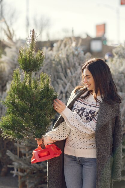 Chica elegante compra un árbol de Navidad.