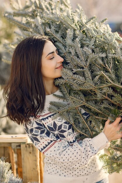 Chica elegante compra un árbol de Navidad.