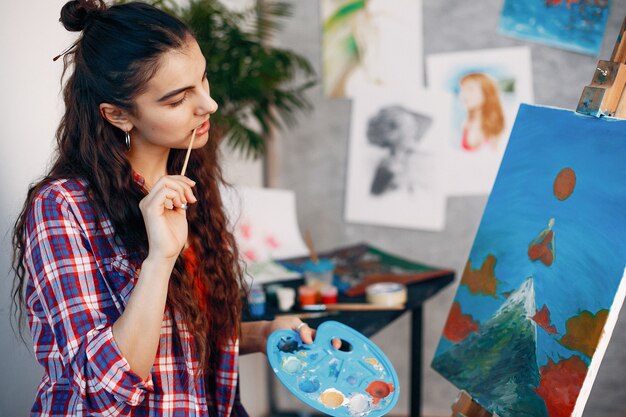 Chica elegante dibuja en un estudio de arte.