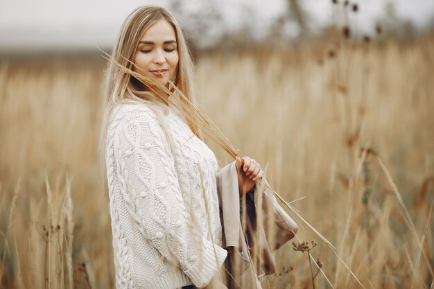 Chica elegante y con estilo en un campo de otoño