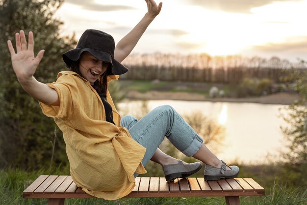 Chica elegante en estilo casual descansa cerca del lago al atardecer por la noche.