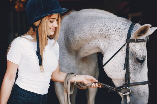 Chica elegante en una granja con un caballo