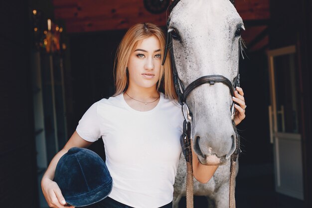 Chica elegante en una granja con un caballo