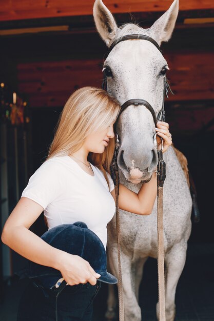 Chica elegante en una granja con un caballo