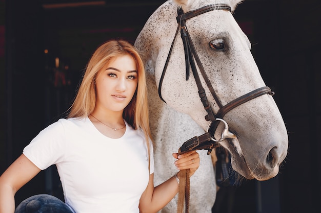 Foto gratuita chica elegante en una granja con un caballo