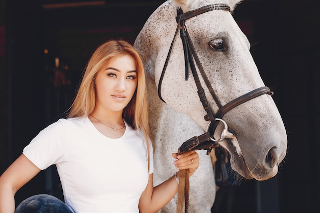 Chica elegante en una granja con un caballo