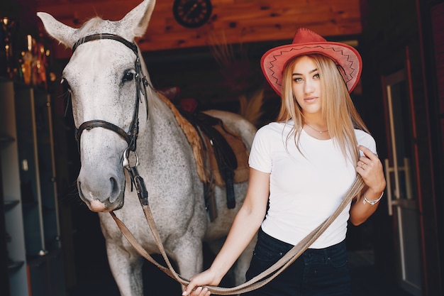 Chica elegante en una granja con un caballo