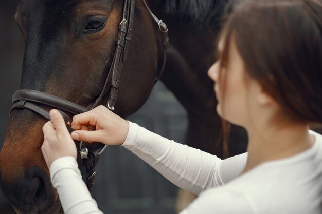 Chica elegante en una granja con un caballo