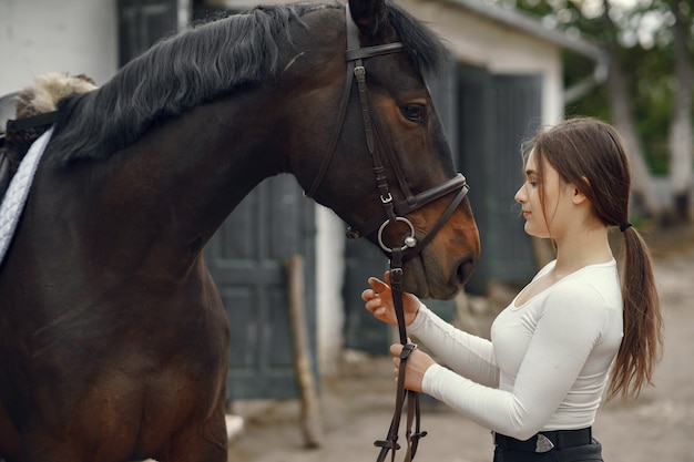 Chica elegante en una granja con un caballo