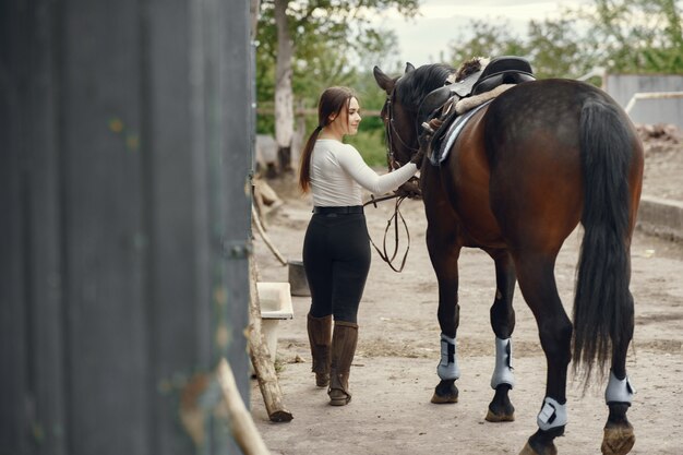 Chica elegante en una granja con un caballo