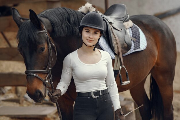 Chica elegante en una granja con un caballo