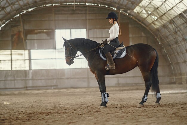 Chica elegante en una granja con un caballo