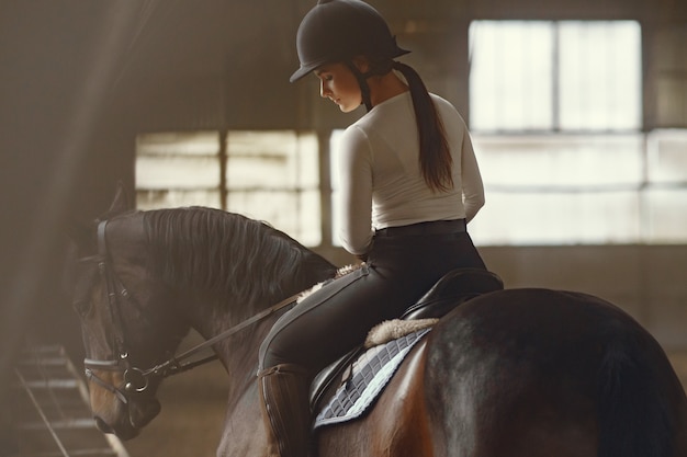 Chica elegante en una granja con un caballo