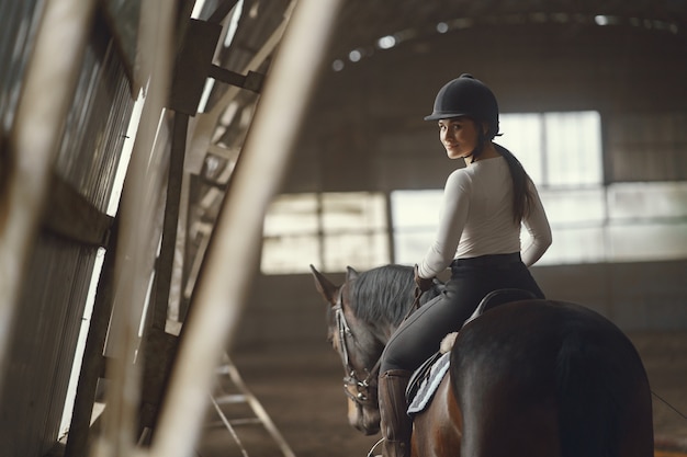 Chica elegante en una granja con un caballo