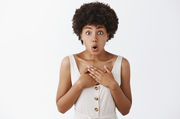 Chica elegante sorprendida posando contra la pared blanca