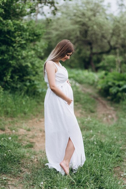 La chica del embarazo se para en la hierba