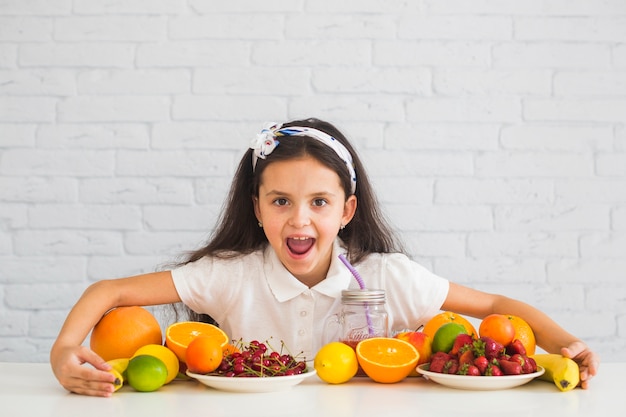 Chica emocionada cubriendo las coloridas frutas orgánicas frescas