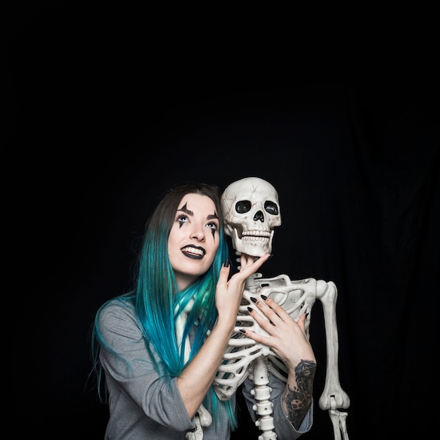 Chica encantadora abrazando el esqueleto de juguete