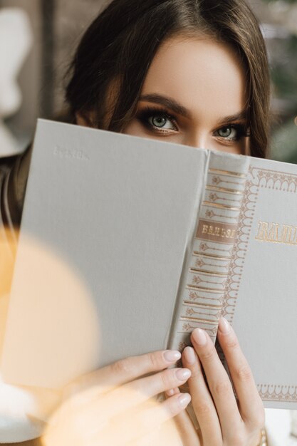 Chica encantadora cerró un libro su cara