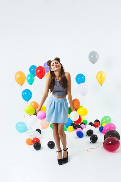 Chica encantadora en look de moda posando con globos pequeños
