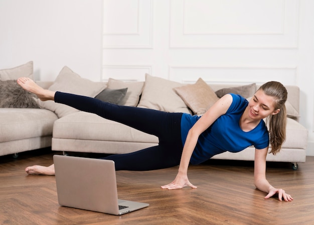 Chica entrenando en casa mientras mira instrucciones