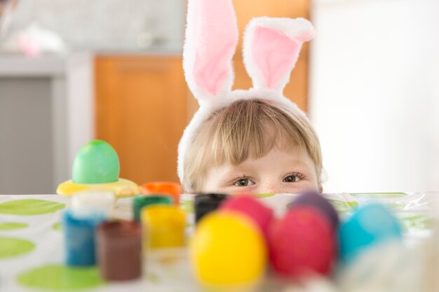 Chica escondida en la mesa con huevos de Pascua