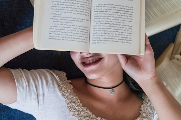 Foto gratuita chica escondiendo su care detrás de un libro