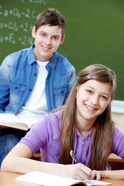 Chica escribiendo con el amigo sonriente de fondo