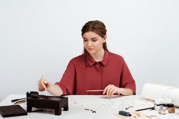 Chica escribiendo caligrafía en postales. Diseño artístico. Encima.