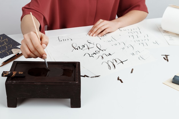 Chica escribiendo caligrafía en postales. Diseño artístico. Encima.