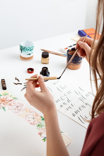 Chica escribiendo caligrafía en postales. Diseño artístico.