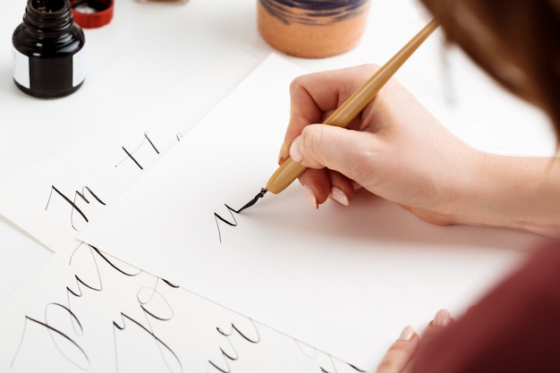 Chica escribiendo caligrafía en postales. Diseño artístico.