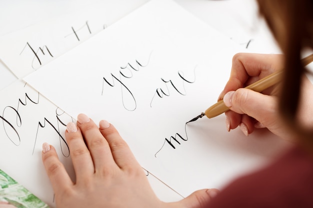 Chica escribiendo caligrafía en postales. Diseño artístico.