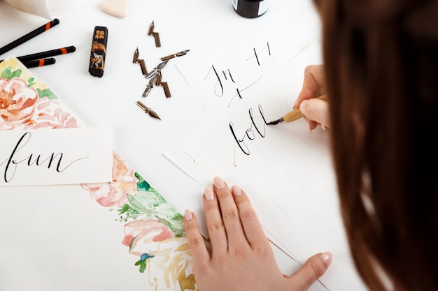 Chica escribiendo caligrafía en postales. Diseño artístico.