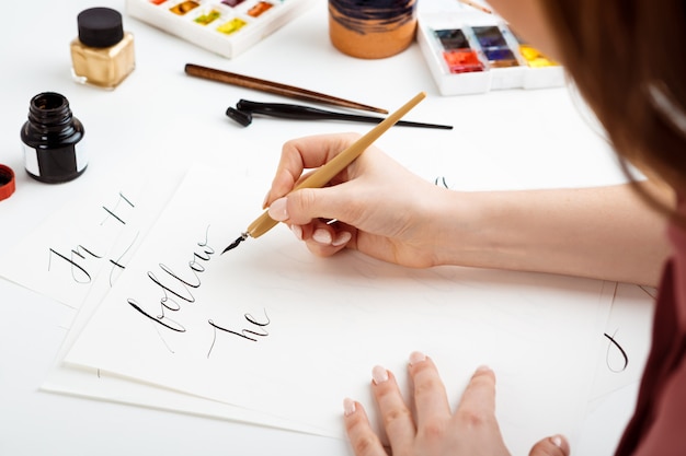 Chica escribiendo caligrafía en postales. Diseño artístico.