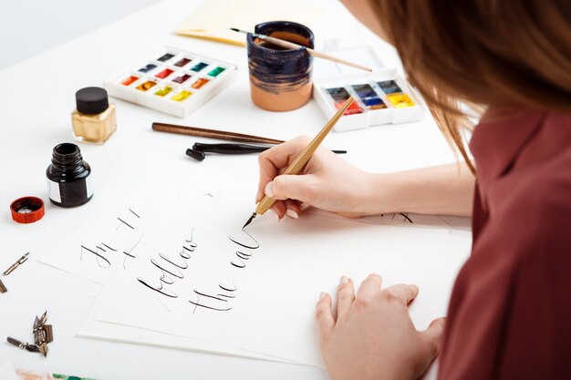 Chica escribiendo caligrafía en postales. Diseño artístico.