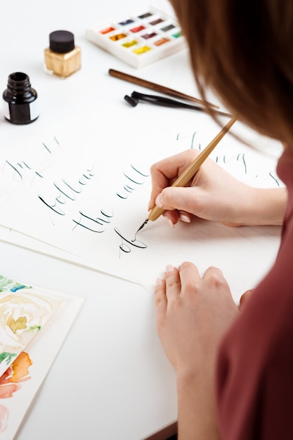 Chica escribiendo caligrafía en postales. Diseño artístico.