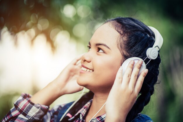 Chica escuchando música con sus auriculares en el bosque